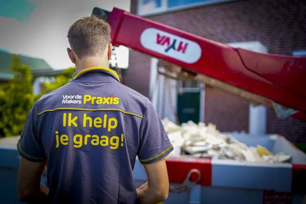 Medewerker klantenservice Praxis-kluscontainer.nl voor een container. Op zijn rug staat de tekst: Wij helpen je graag!